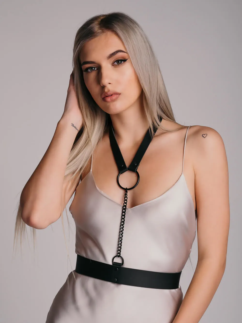 Brave leather harness accessory with choker with large black ring and black chain connected to belt.